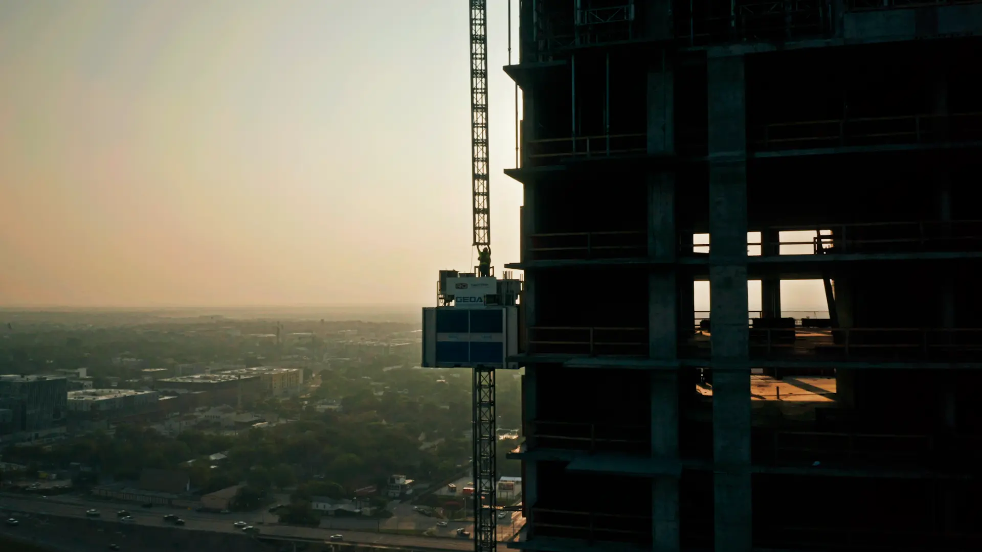 High-rise construction tower silhouetted against an Austin sunrise